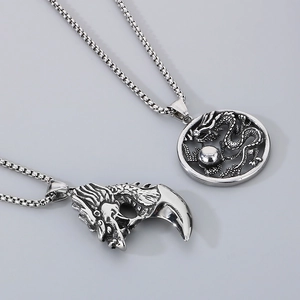 Détail de deux pendentifs dragon en argent avec des sculptures vintage sur chaîne en métal