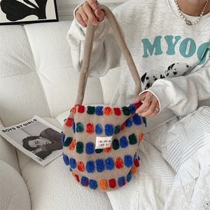 Detail of a beige plush bucket bag featuring colorful polka dots and a fuzzy shoulder strap