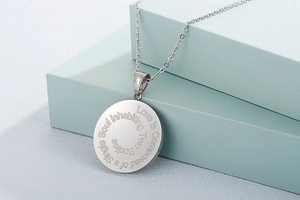 Macro view of silver stainless steel round pendant with engraved romantic quote detail
