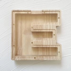Close-up of oak wood letter E money box with transparent panel and golden screws