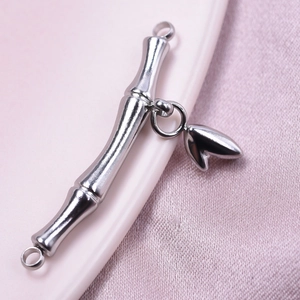 Detailed view of silver bamboo T-bar clasp with leaf charm on smooth pink fabric