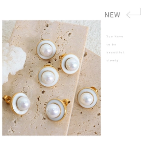 Detailed view of elegant round pearl earrings with gold frames on a natural stone surface