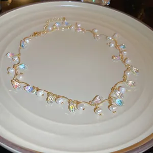Detail of gold vine chain necklace with white pearls and faceted crystal pendant in a tray