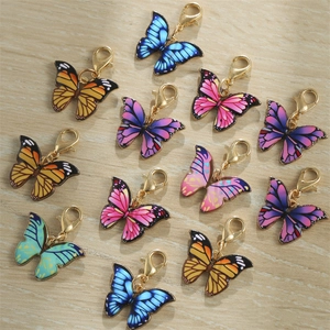 Colorful enamel butterfly charms with golden lobster clasps on light wood background