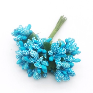 Close-up of blue artificial berry cluster with green leaves for DIY wedding craft decor
