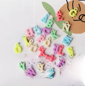 Dettaglio macro di ciondoli con lettere in acrilico color macaron per gioielli fai-da-te