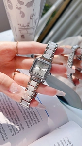 Close-up of square silver watch with rhinestone bezel and white ceramic link bracelet