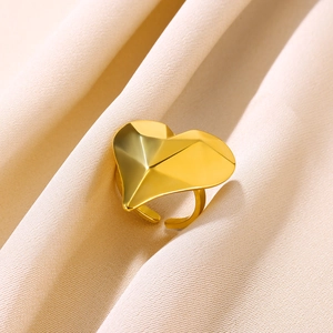 Detail of adjustable gold heart ring with geometric facets on a soft fabric background