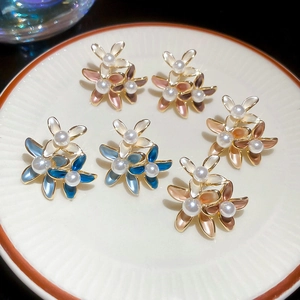 Detail of floral earrings with pearls and colorful enamel on a white ceramic plate