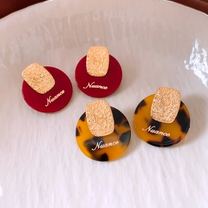 Close-up of vintage acetate earrings with gold metal accents in burgundy and tortoiseshell