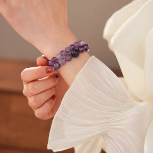Nahaufnahme von zweilagigen Amethyst-Perlenarmbändern am Handgelenk einer Frau