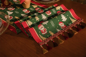Detail of woven Christmas table runner with Santa Claus pattern and golden tassels