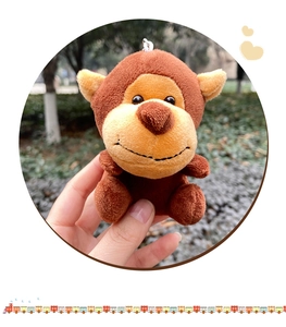 Close-up of a cute brown plush monkey keychain with soft fur and a metal chain link