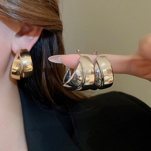 Close-up of chunky silver double-layered C-shaped metal hoop earrings with polished finish