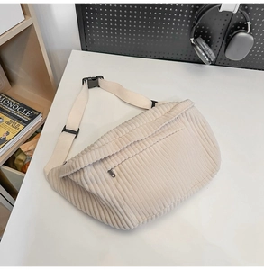 Close-up of beige corduroy crossbody bag with adjustable strap on a minimal desk