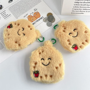 Close-up of cute plush potato coin purses with green metal carabiners on a desk