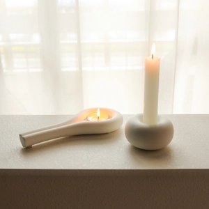Minimalist white ceramic candle holders set for pillar and tea light on a sunny windowsill