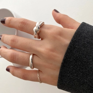Detailed view of silver minimalist irregular twisted and chain rings on hand with cup