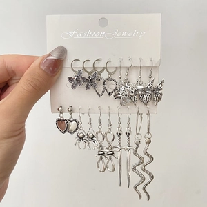 Detail of vintage silver earring set featuring heart, butterfly, snake, and sword charms
