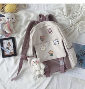 Detail of canvas backpack in beige and purple featuring cute bear and rabbit badges