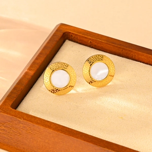 Close-up of gold-plated titanium earrings with white inlay in a luxury wooden box