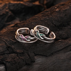 Vintage silver twist cross rings with pink and green zircon stones on wooden background