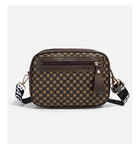 Detail of a brown quilted camera bag featuring golden monogram patterns and a wide strap