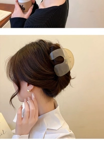 Detail showing a matte beige hair claw clip on a model with elegant updo hairstyle