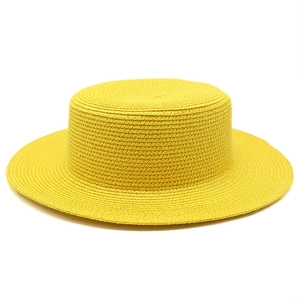 Close-up of bright yellow flat-top straw hat showing fine weaving texture for summer