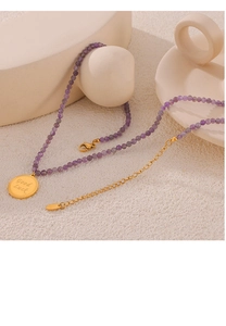 Detail einer Amethyst-Perlenkette mit goldenem Good Luck Anhänger und Karabinerverschluss