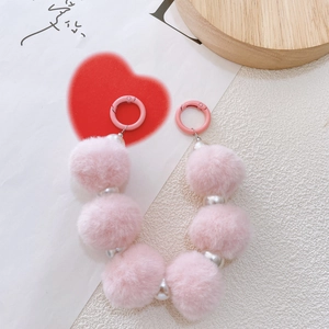 Detailed close-up of pink pompom and pearl chain with pink metal spring ring clasp