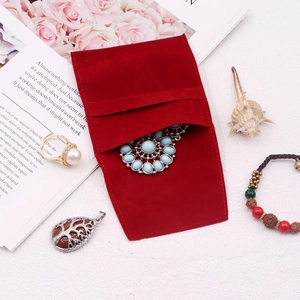 Close-up of a red velvet jewelry pouch with pearl necklace and gemstone accessories
