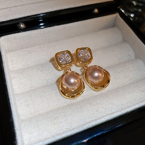Vue macro de boucles d'oreilles vintage avec cristal carré et perle rose en boîte