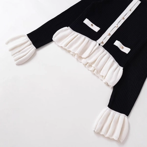 Elegant knit cardigan with contrasting white pleated cuffs and gold-embossed buttons