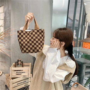 Detail of corduroy checkerboard tote bag with top handle and metal snap button closure