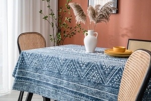 Close-up of blue geometric pattern linen tablecloth on a dining table with rattan chairs