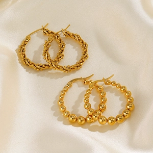 Élégantes boucles d'oreilles créoles dorées torsadées et perlées sur tissu en soie