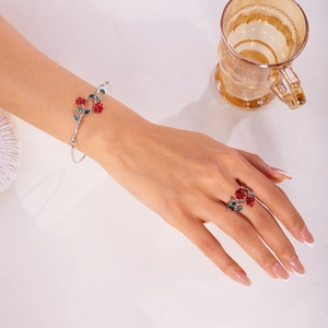 Detailed view of red rose enamel open bracelet and matching ring set on a model