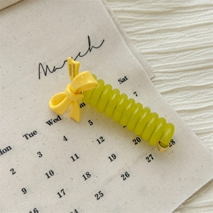 Detail of yellow bow spiral hair tie on a March calendar background with flat lay style