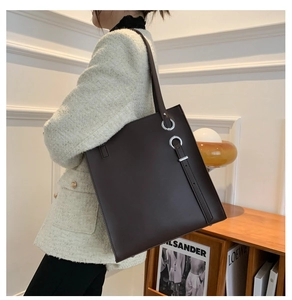 Detail of dark brown leather tote bag with silver metal ring accents on shoulder strap