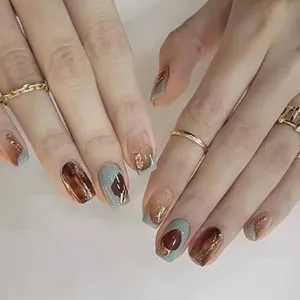 Close-up of Morandi blue and amber press-on nails with gold glitter and metallic accents