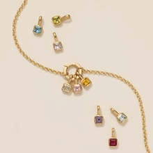 Détail d'un collier doré avec plusieurs pendentifs en pierres précieuses carrées colorées