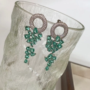 Vue macro de boucles d'oreilles pampilles émeraude avec zircone sur anneaux en argent