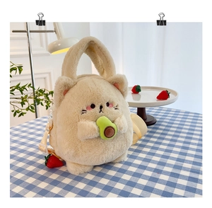 Plush beige cat bag holding an avocado with adjustable strap on a checkered tablecloth