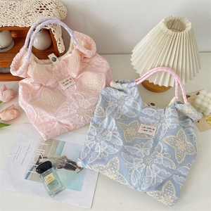 Détail de la broderie papillon sur des sacs cabas en toile avec étiquette de marque chic