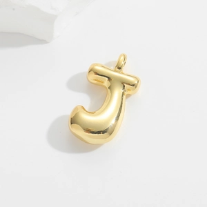 Detailed view of a golden balloon-style letter J pendant on a minimalist white stone background