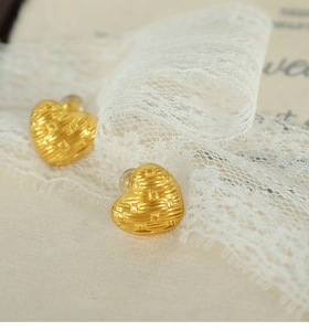 Detailed view of French vintage woven heart earrings in gold finish on lace background