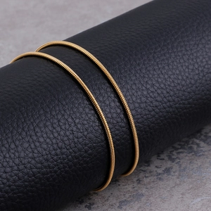 Detailed close-up of a 1.5mm golden stainless steel snake chain on black leather stand