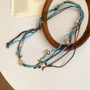 Detail of bohemian suede necklace with blue and brown leather cords and silver metal accents