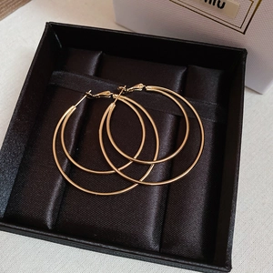 Double-layered golden circular hoop earrings showcased in a black satin gift box